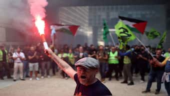 A French SNCF railway worker on strike holds a red flare as they gather inside the Bercy Economy and Finance Ministry in Paris as part of a day of nationwide strikes and protests against the government and cuts in the next budget in France. Reuters