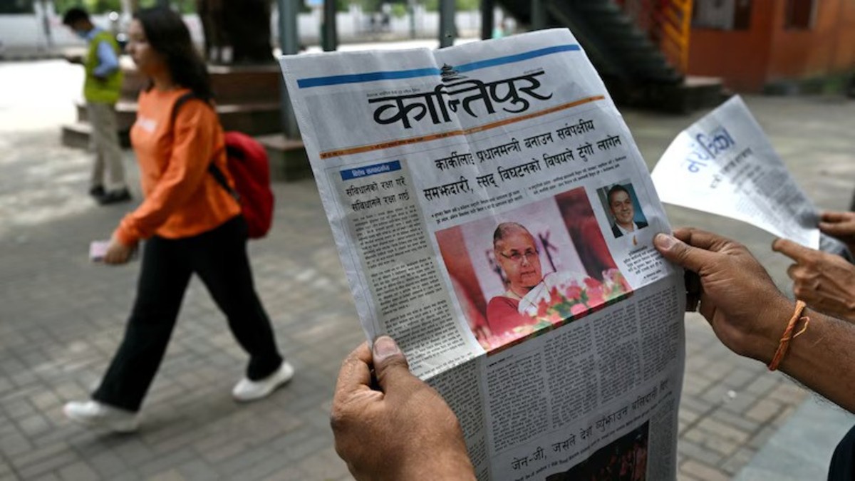 A man reads a Nepali-language newspaper on a roadside in Kathmandu on September 12, 2025, featuring the country's former chief justice Sushila Karki with headlines related to ongoing unrest in Nepal. File image/ Moneycontrol  A man reads a Nepali-language newspaper on a roadside in Kathmandu on September 12, 2025, featuring the country's former chief justice Sushila Karki with headlines related to ongoing unrest in Nepal. File image/ Moneycontrol