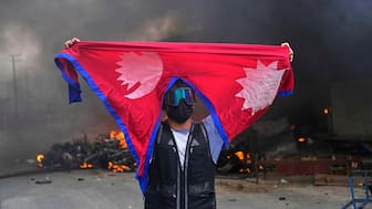A protester shouts slogans carrying national flag after burning down a police station during protests against social media ban and corruption in Kathmandu, Nepal, Tuesday, Sept. 9, 2025.  AP