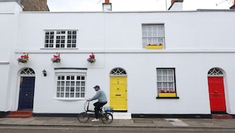 A cyclist rides past house doors painted blue, yellow and red in Britain. One of the simplest and most effective ways to cool a building is to change its colour. Representational image/Reuters