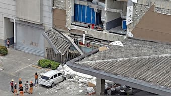 A security guard walks past a damaged wall and a car outside a mall in Butuan City, on the southern island of Mindanao on October 10, 2025, after a 7.4-magnitude earthquake struck off the southern Philippines. AFP