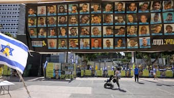 People walk past posters of hostages held by the Palestinian militant group Hamas in Gaza at Hostage Square in Tel Aviv on October 10, 2025. AFP