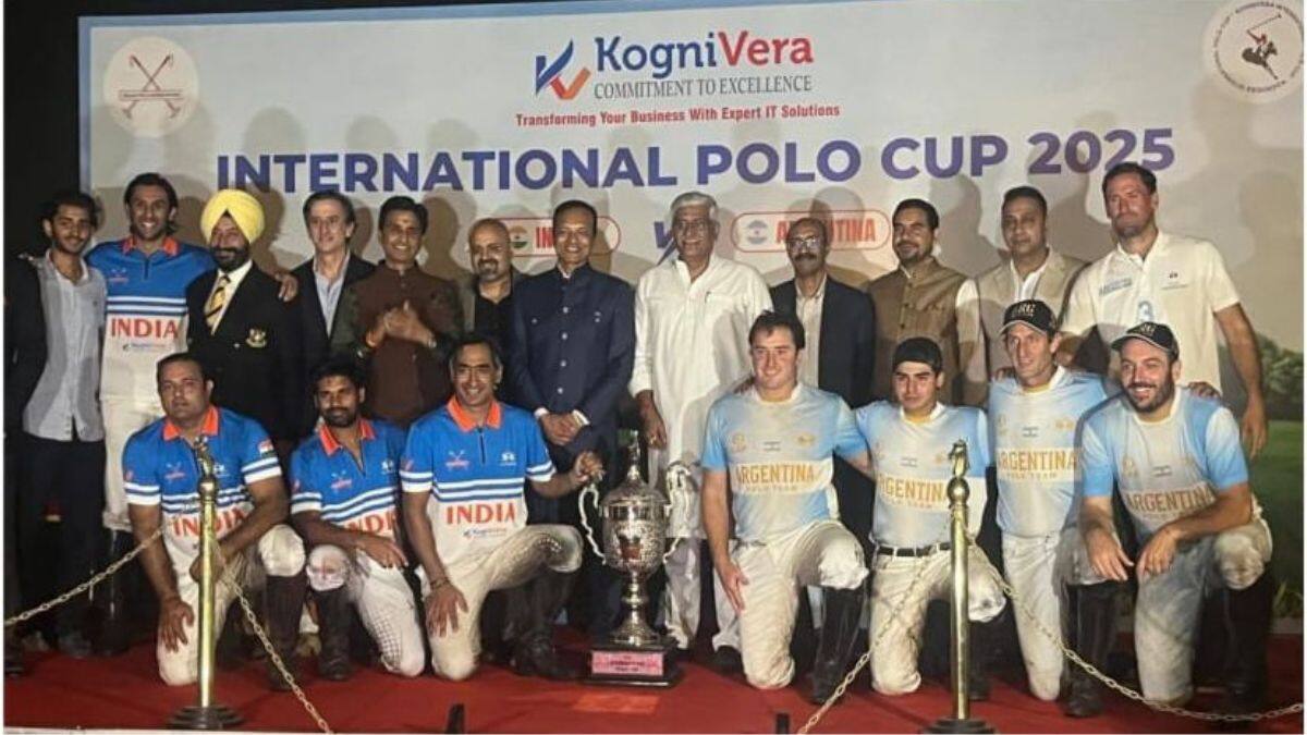 Players from India and Argentina can be seen posing with the International Polo Cup trophy along with IPA officials and other dignitaries at the Jaipur Polo Ground, in New Delhi, India on October 25, 2025. Firstpost via KogniVera