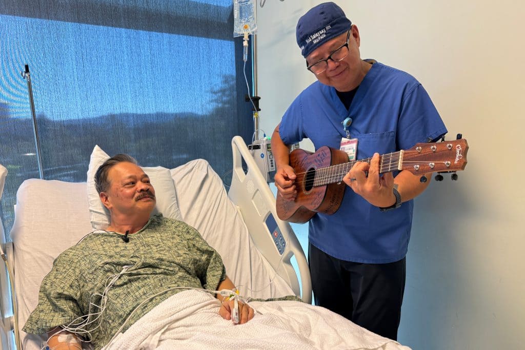 Nurse Rod Salaysay plays guitar for patient Richard Hoang in the recovery unit of UC San Diego Health in San Diego, California. AP