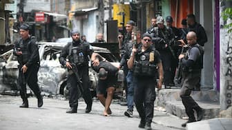 Police officers escort a suspect arrested during the Operacao Contencao (Operation Containment) out of the Vila Cruzeiro favela, in the Penha complex, in Rio de Janeiro, Brazil, on Tuesday. AFP