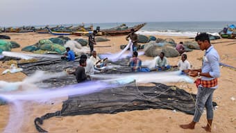 Fishermen repair their nets on a beach after the authorities issued advisories against venturing into the sea as a precautionary measure against Cyclone 'Montha', in Puri. PTI