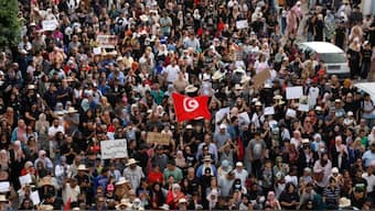 File- Protesters carry placards and wave national flags as they march in the city of Gabes. [Mohamed Khalil/AFP]