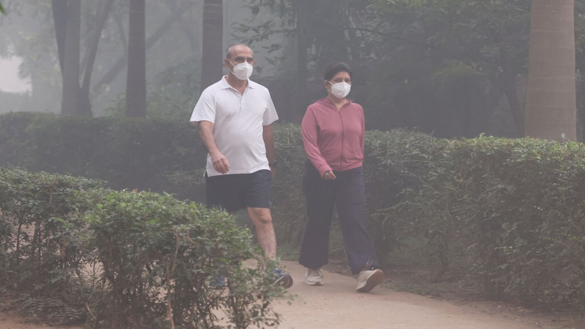 People walk wearing face masks at a park amidst smog in New Delhi. Reuters People walk wearing face masks at a park amidst smog in New Delhi. Reuters