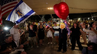 A person wearing a Trump mask waves an Israeli flag, as people celebrate after the US president announced that Israel and Hamas agreed on the first phase of a Gaza ceasefire, at the "Hostages square", in Tel Aviv, Israel. Reuters file