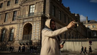 A woman makes a selfie in front of the facade and the window where thieves entered the Louvre museum last Sunday. AP