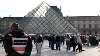 A security guard stands in front of the Pyramide du Louvre, designed by Chinese-US architect Ieoh Ming Pei, with the Louvre Museum in the background in Paris. The Louvre Museum has reopened its doors to visitors aftet the October 19 robbery by four criminals, who made off with eight jewels. AFP