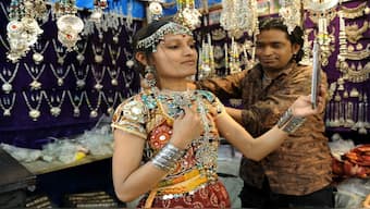 A young woman tries oxidised jewellery at a shop in Ahmedabad. India, the world's largest consumer of silver, uses the metal in silverware, jewellery, coins, and bars. File image/AFP
