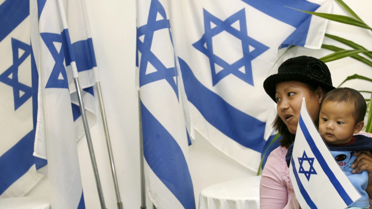 A newly arrived Jewish immigrant from India holds a child beside Israeli flags after arriving at Ben Gurion international airport near Tel Aviv. File image/Reuters A newly arrived Jewish immigrant from India holds a child beside Israeli flags after arriving at Ben Gurion international airport near Tel Aviv. File image/Reuters