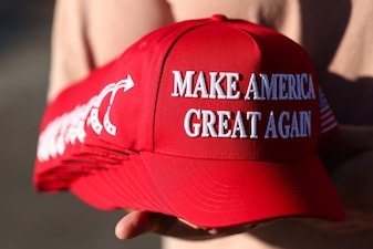 A member of Turning Point USA distributes Maga hats. File image/AFP