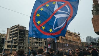 A protester waves an anti-EU and anti-NATO flag as Serbian students and Belgrade residents gather for a protest in Belgrade on November 11, 2025, against a plan by Jared Kushner, the son-in-law of US President, to demolish the former Yugoslav army headquarters and build a luxury hotel on the site.  (Photo by Andrej ISAKOVIC / AFP)