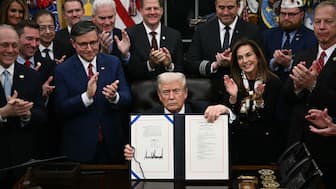 US President Donald Trump shows the signed bill package to re-open the federal government in the Oval Office of the White House in Washington, DC, on November 12, 2025. AFP