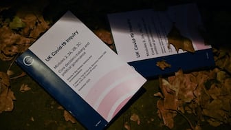 Copies of a new report on government decision-making during the Covid-19 pandemic are pictured as family members who lost loved ones from Covid speak to the media, next by the National Covid Memorial Wall in central London. AFP