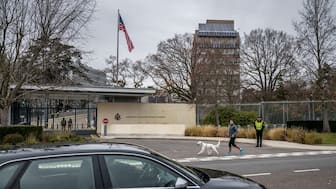 A man jogs with his dog outside the Missions of the United States of America in Geneva, on November 23, 2025 ahead of discussions on a US plan to end the war in Ukraine. US Secretary of State Marco Rubio arrived in Geneva on November 23, 2025 morning for discussions on a US plan to end the Ukraine war, after Washington signalled room for negotiation on the controversial proposal. Ukrainian, European and Canadian officials were also gathering in the Swiss city. (Photo by Fabrice COFFRINI / AFP)