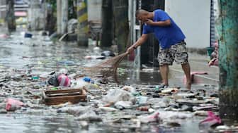 A man cleans garbage along a flooded street due to Typhoon Fung-wong and high tide on Monday, Nov. 10, 2025, in Navotas, Philippines. AP