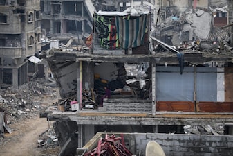 A woman sits inside her damaged apartment, surrounded by the the rubble of neighboring residences, all devastated by Israeli bombardments, in Gaza City, Friday Nov.14, 2025. (AP Photo/Yousef Al Zanoun)