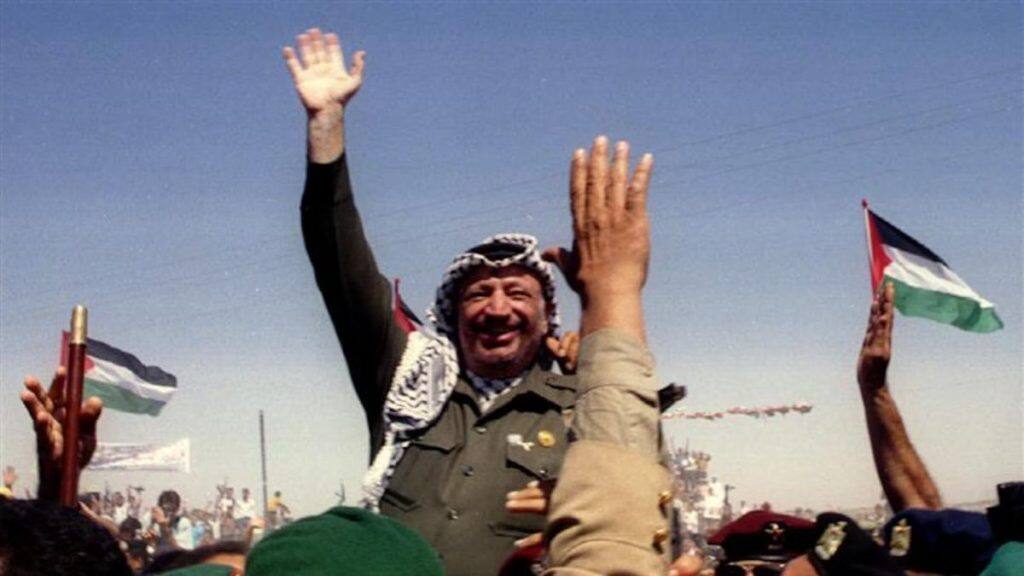 Palestine Liberation Organization (PLO) chairman Yasser Arafat waves as he is briefly lifted on the shoulders of Palestinian police, moments after entering the Gaza Strip at Rafah. Reuters