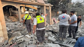 Members of civil defence stand on rubble at a damaged site after Israeli strikes following Israeli military's evacuation orders, in Tayr Debba, southern Lebanon on Thursday. Reuters