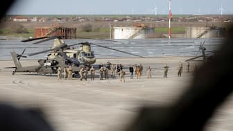 US Army troops near a CH-47 Chinook and a AH-64E attack helicopter at MK Airbase, in Mihail Kogalniceanu, Constanta county, Romania, on Tuesday. Reuters