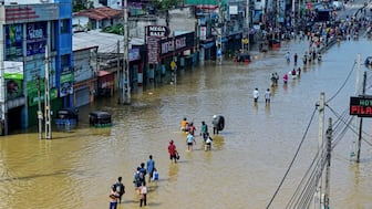 People wade through a flooded street after heavy rainfall in Wellampitiya on the outskirts of Colombo on November 30, 2025.- AFP