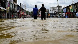 Residents wade through a flooded street after heavy rainfall. Image Credit: AFP