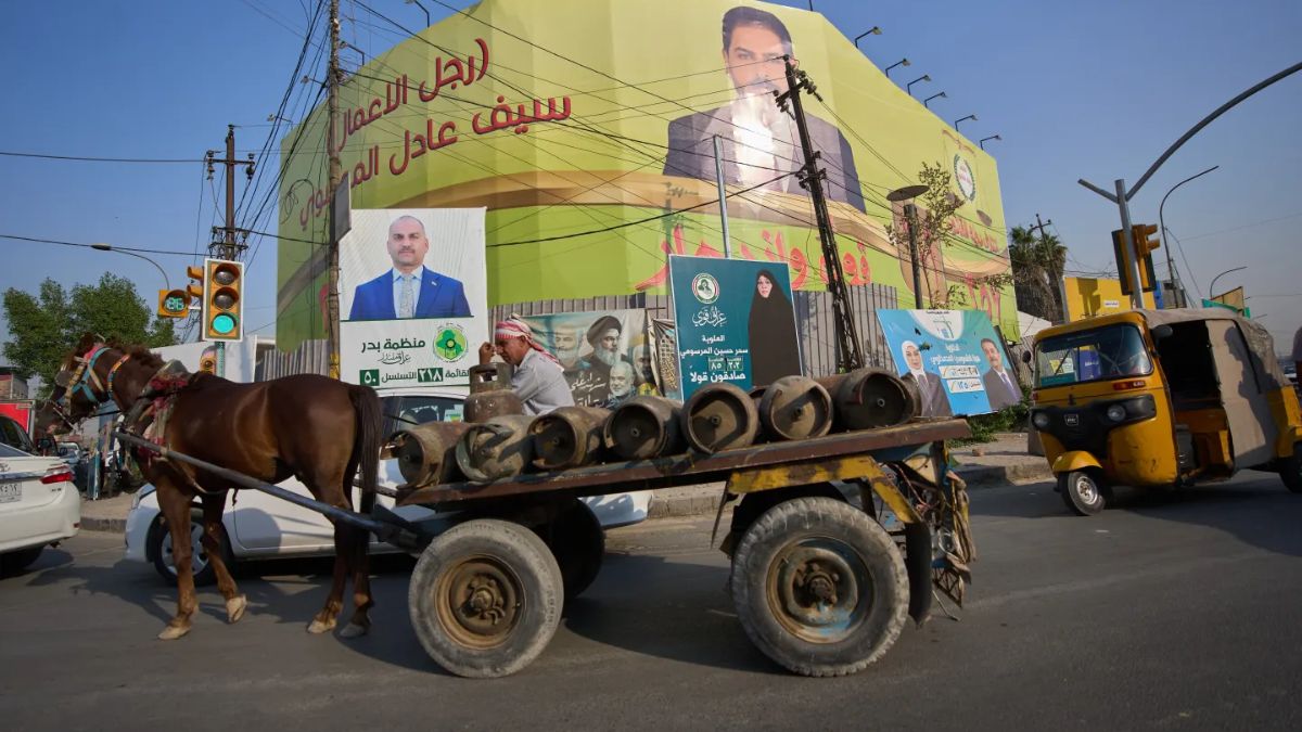 A laborer riding a horse cart carrying cooking gas cylinders, passes elections posters in Baghdad, Iraq (Image: AP) A laborer riding a horse cart carrying cooking gas cylinders, passes elections posters in Baghdad, Iraq (Image: AP)