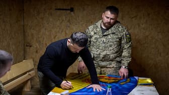 Ukraine's President Volodymyr Zelenskyy signs a flag of the 65th Separate Mechanized Brigade 'Velykyi Luh' while he visits their command position at a front line, amid Russia's attack on Ukraine, in Zaporizhzhia region, Ukraine, on November 13, 2025. Reuters File

