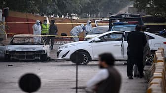 Forensic experts examine a car after a suicide blast outside the district court in Islamabad, which killed at least 12 people. AFP