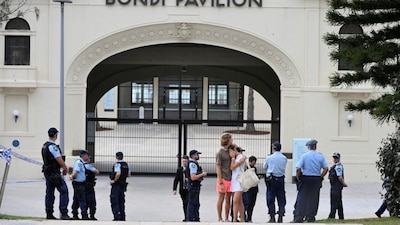 Two people embrace as police officers stand guard outside Bondi Pavilion following the attack on a Jewish holiday celebration at Sydney's Bondi Beach, in Sydney, Australia, December 15, 2025. Reuters