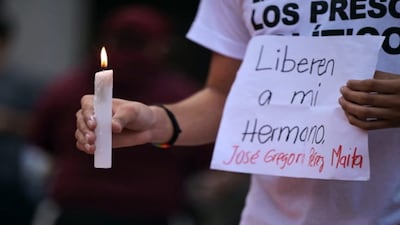 A man holds a candle and a sign asking for the release of his brother during a vigil for political prisoners in Caracas, Venezuela, on 8 August 2024. AFP