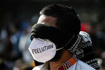 A demonstrator wearing a mask takes part in a protest demanding the government take action to reduce air pollution in New Delhi on December 3, 2025. (Photo by Sajjad HUSSAIN / AFP)