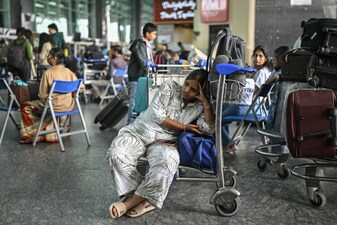 A passenger waits outside the IndiGo Airlines kiosk at the Kempegowda International Airport in Bengaluru on December 6, 2025.  (AFP)