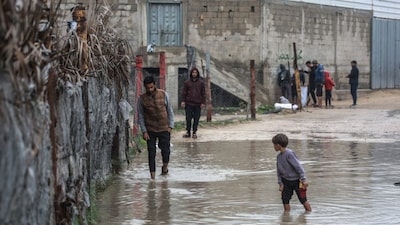 A man walks through a waterlogged alley in Deir al-Balah, in the central Gaza Strip, on December 11, 2025. AFP