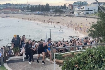 This screen grab of UGC video taken on December 14, 2025 and received courtesy of Mike Ortiz shows beach-goers fleeing Bondi Beach after gunmen opened fire, in Sydney on December 14, 2025.  (AFP)