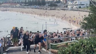 This screen grab of UGC video taken on December 14, 2025 and received courtesy of Mike Ortiz shows beach-goers fleeing Bondi Beach after gunmen opened fire, in Sydney on December 14, 2025.  (AFP)