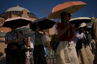 Tourists use umbrellas to shelter against the sun outside Hagia Sophia mosque during a hot summer day in Istanbul. File image/AP
