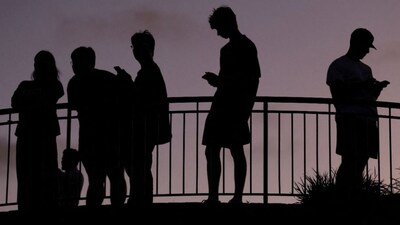 People use their mobile phones, ahead of new law banning social media for users under 16 in Australia, at dusk in Brisbane, Australia, December 8, 2025. File Image/Reuters