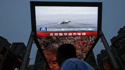 A person looks at a screen showing news footage of military drills conducted in areas around the island of Taiwan by the Eastern Theatre Command of the Chinese People's Liberation Army (PLA), in Beijing, China, on May 23, 2024. Reuters File