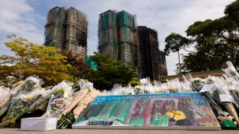 A painting depicting a photograph taken by Reuters photographer Tyrone Siu sits at a makeshift flower memorial nearby to the Wang Fuk Court housing complex residents after the deadly fire, in Tai Po, Hong Kong, China, on Monday. Reuters