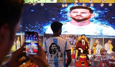 A fan poses for a photograph inside a temporary museum honouring soccer player Lionel Messi's long career ahead of his India tour. Reuters