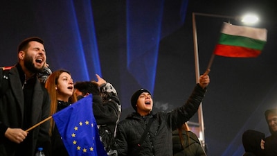 Protesters wave Bulgarian and EU flags during an anti-government demonstration in Sofia on December 10, 2025.- AFP