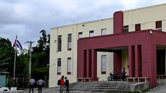 People stand at the entrance of the courthouse where Cuba's former Economy Minister Alejandro Gil stands trial on espionage charges, Havana, Cuba, November 11, 2025. Image Credit: Reuters