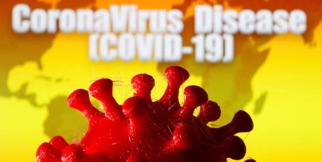 A 3D-printed coronavirus model is seen in front of a world map and the words 
