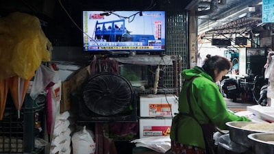A woman works in a noodle store near a television screen showing a news report on China's "Justice Mission 2025" military drills around Taiwan, in Taipei, Taiwan. Reuters