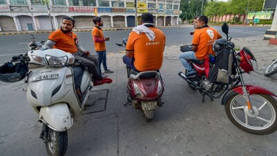 Deliverymen of food aggregator Swiggy wait along a roadside in New Delhi. File image/PTI