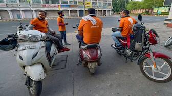 Deliverymen of food aggregator Swiggy wait along a roadside in New Delhi. File image/PTI
